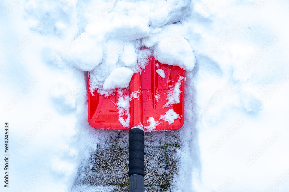 Snow removal in winter, Snowfall, Red shovel lying in the snow. Seasonal concept, difficult weather conditions - obrazy, fototapety, plakaty 