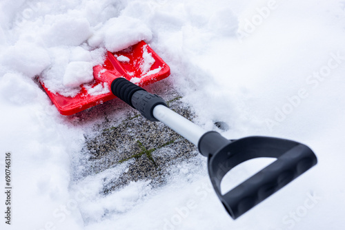 Snow removal in winter, Snowfall, Red shovel lying in the snow. Seasonal concept, difficult weather conditions