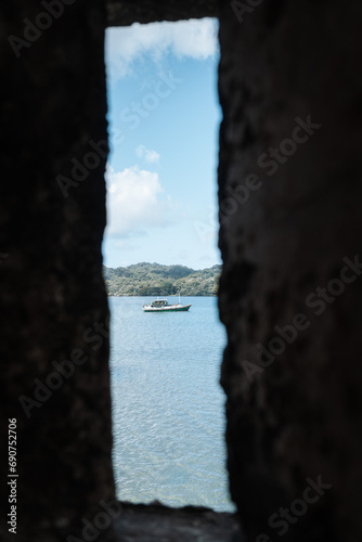Small boat can be seen through an opening of a stone wall