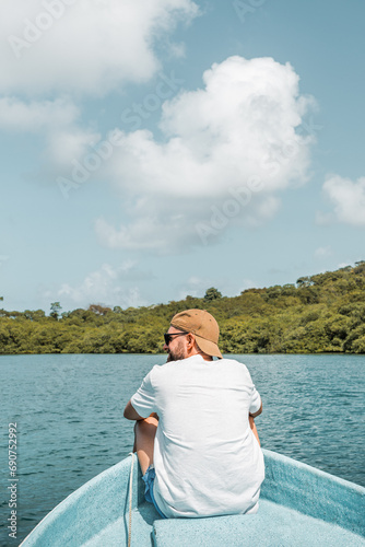 Man with cap and sunglasses sitting on the edge of a boat floating © Nestor