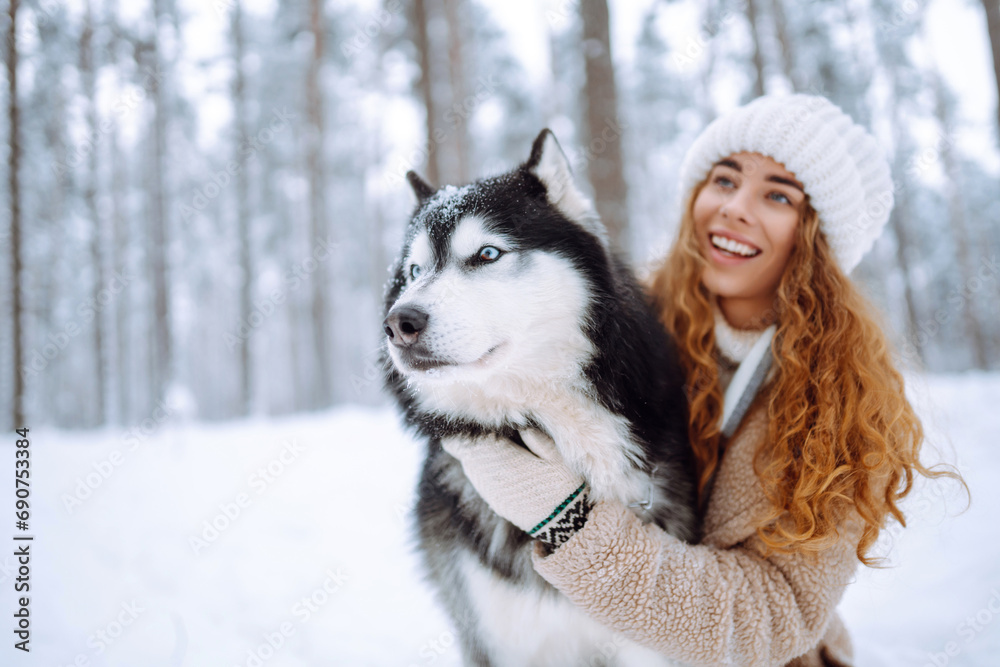 Cute woman spends time with her husky dog in the winter snowy forest. Happy pet dog owner having fun together outdoors. Fun concept. Lifestyle. Cute woman spends time with her husky dog in the winter snowy forest. Happy pet dog owner having fun together outdoors. Fun concept. Lifestyle.