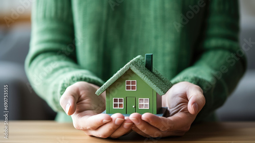 Woman's hands gently holding a miniature house model, symbolizing home ownership or real estate