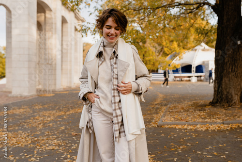 pretty smiling woman walking in park in autumn clothes