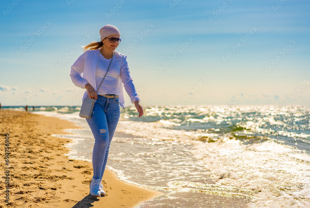Beautiful mid adult woman walking on sunny beach
