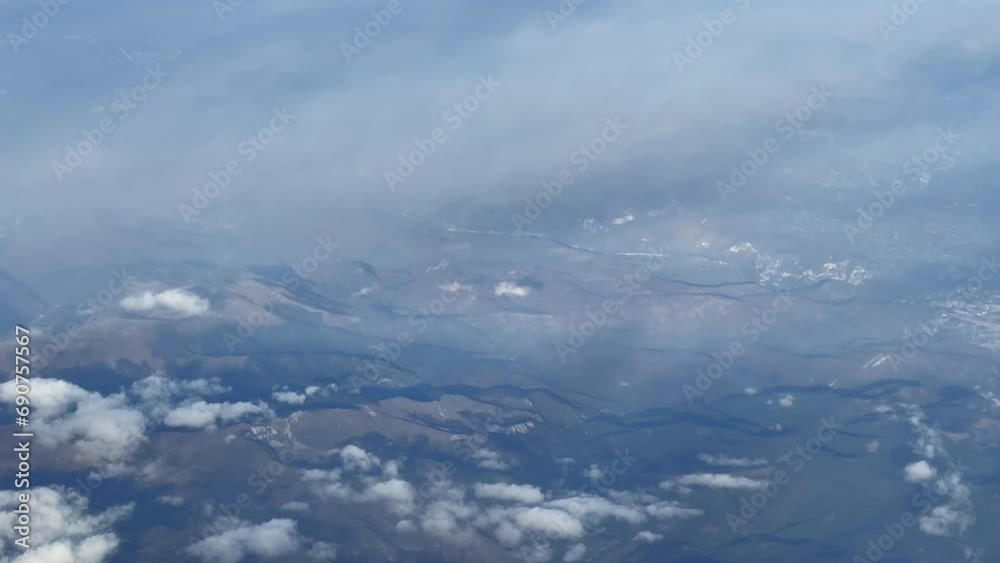 Aerial view from an airplane's window flying over the clouds Aerial view from an airplane's window flying over the clouds