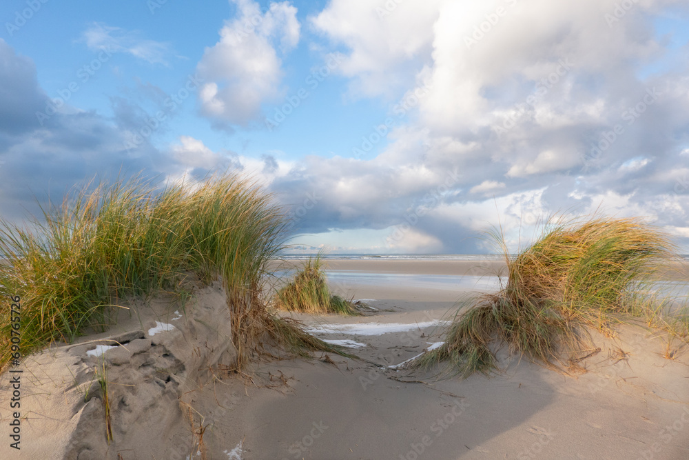 View on vast beach and sea between two dunes grown with Marram grass