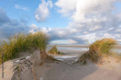 View on vast beach and sea between two dunes grown with Marram grass