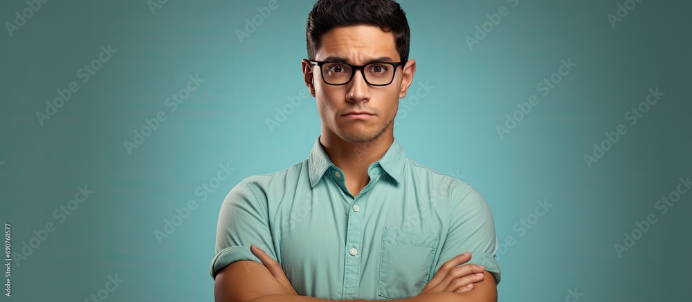 Young hispanic man wearing casual clothes and glasses skeptic and nervous disapproving expression on face with crossed arms negative person. Copyspace image. Header for website template - obrazy, fototapety, plakaty 