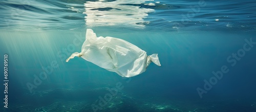 Underwater pollution A discarded plastic carrier bag drifting in a tropical blue water ocean. Copyspace image. Square banner. Header for website template