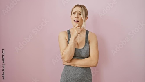 Unwell blondie in sports get-up coughing over pink, isolated backdrop. possible bronchitis? reminder of health care's importance.