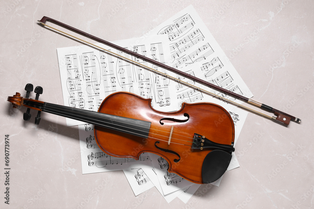 Fototapeta premium Violin, bow and music sheets on grey marble table, top view