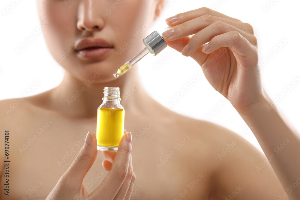 Fototapeta premium Beautiful young woman with bottle of cosmetic serum on white background, selective focus