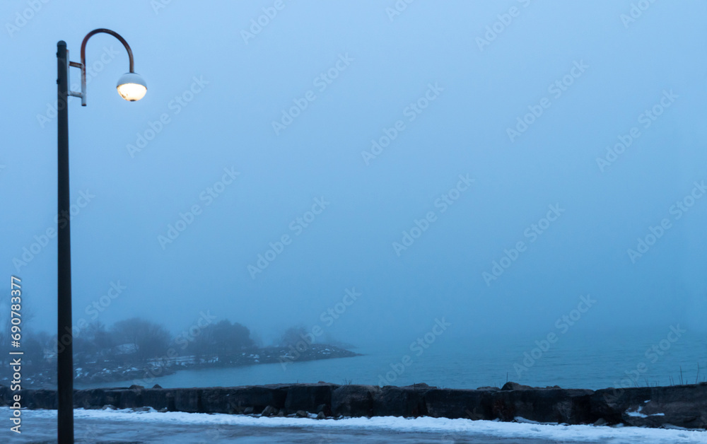 Rainy foggy weather at the lake. Misty fog blowing over water coast and trees. Cold foggy rainy winter evening. Scarborough Bluffs or The Bluffs Ontario lake waters.