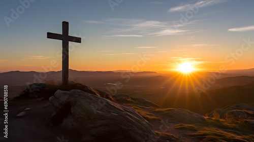 Christian cross on top of a hill facing the rays of a new dawn rising from the horizon. Symbolic of the resurrection of Jesus Christ, hope through faith, a new beginning. photo