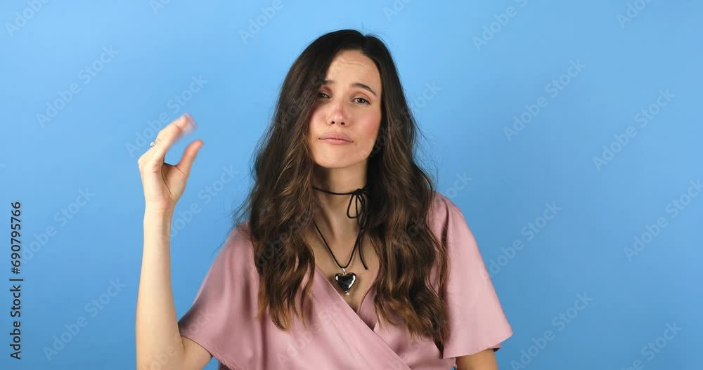 Brunette indignant woman showing blah blah blah gesture with hands isolated on studio blue background. Empty promises, blah concept. Lier, not interested. Annoyed girl making bla bla bla hand gesture. Brunette indignant woman showing blah blah blah gesture with hands isolated on studio blue background. Empty promises, blah concept. Lier, not interested. Annoyed girl making bla bla bla hand gesture.