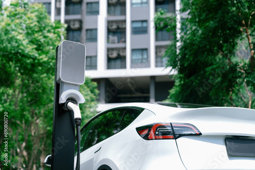 Fototapeta Naklejka Na Ścianę i Meble -  EV electric car charging in green sustainable city outdoor garden in summer. Urban sustainability lifestyle by green clean rechargeable energy of electric BEV vehicle innards