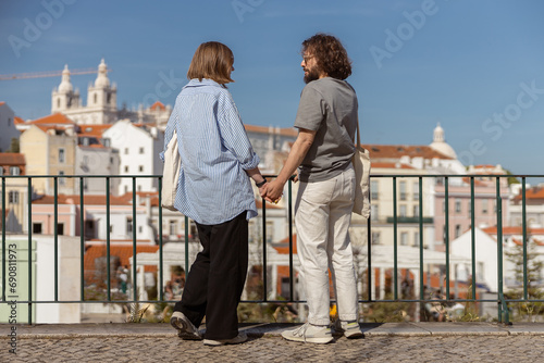 Back view of couple in love holding hands while walking on old city street. High quality photo