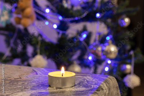 A burning candle against the background of a New Year tree. Blackout due to the war in Ukraine