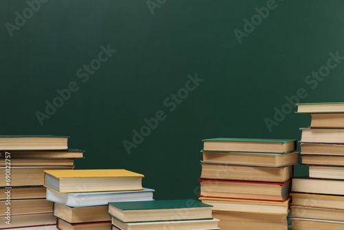 Many hardcover books near green chalkboard, space for text. Library material