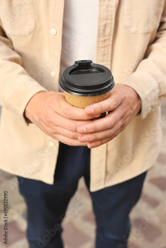 Coffee to go. Man with paper cup of drink outdoors, closeup © New Africa