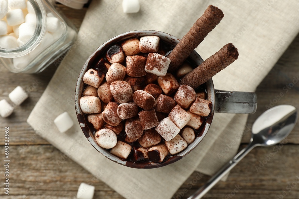 Delicious hot chocolate with marshmallows and cocoa powder in cup on wooden table, flat lay Delicious hot chocolate with marshmallows and cocoa powder in cup on wooden table, flat lay