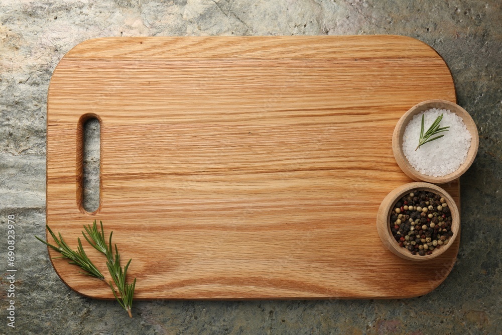 Wooden cutting board and spices on textured table, top view. Space for text Wooden cutting board and spices on textured table, top view. Space for text