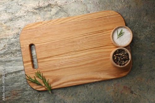 Wooden cutting board and spices on textured table, top view. Space for text
