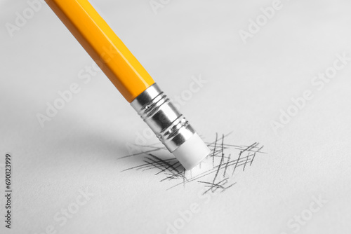 Erasing scribbles with graphite pencil on white background, closeup