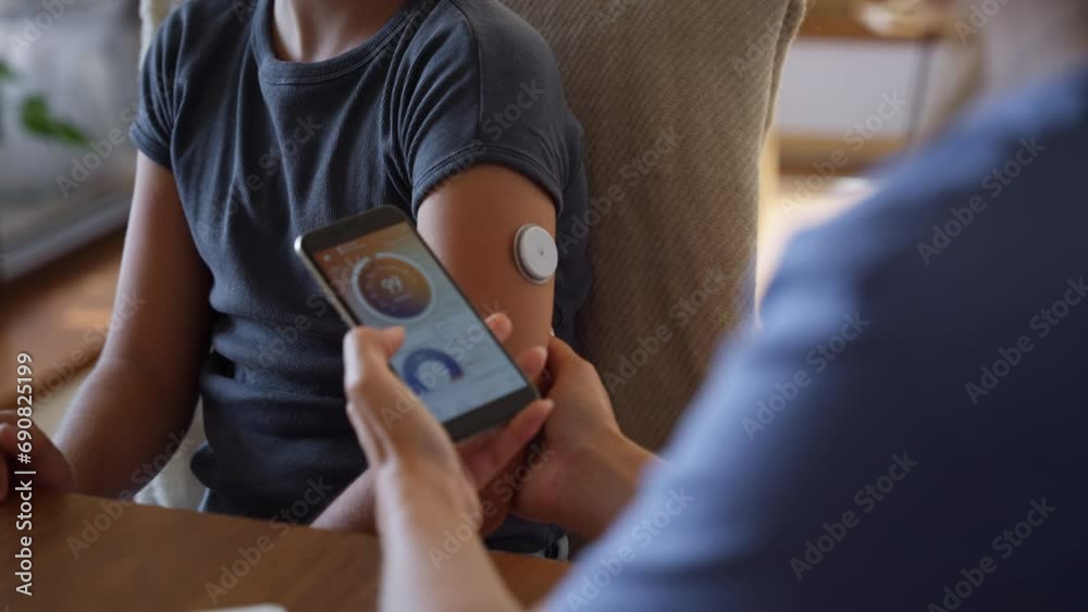 Girl with diabetes checking blood glucose level at home using continuous glucose monitor.