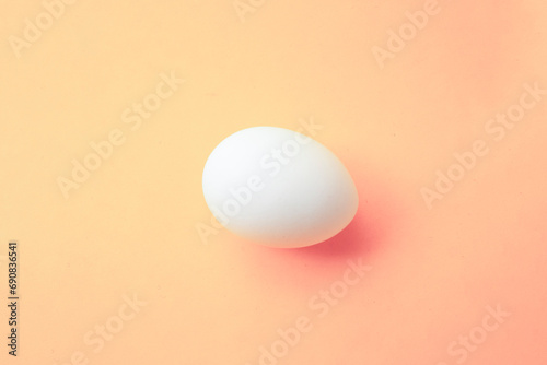 One white chicken egg on an peach background. Preparing for Happy Easter. Food photo. Empty egg for coloring. Coloring book for children. Trendy modern beige color 2024. Light pastel pink color