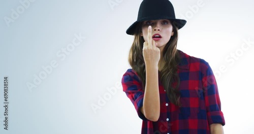 Rude, sign and woman with middle finger and face in white background and studio to show anger. Frustrated, gesture and angry portrait of person with mean emoji to signal a curse, conflict or problem photo
