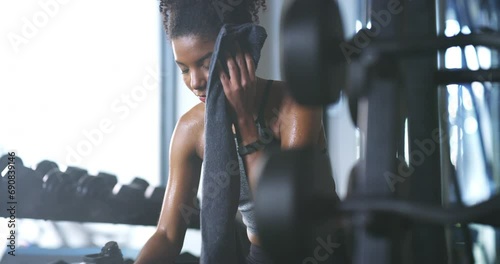Gym towel, sweat or woman tired, relax or rest after active training, workout routine or body building challenge burnout. Fitness fatigue, recovery or African person exercise, exhausted and wipe face photo