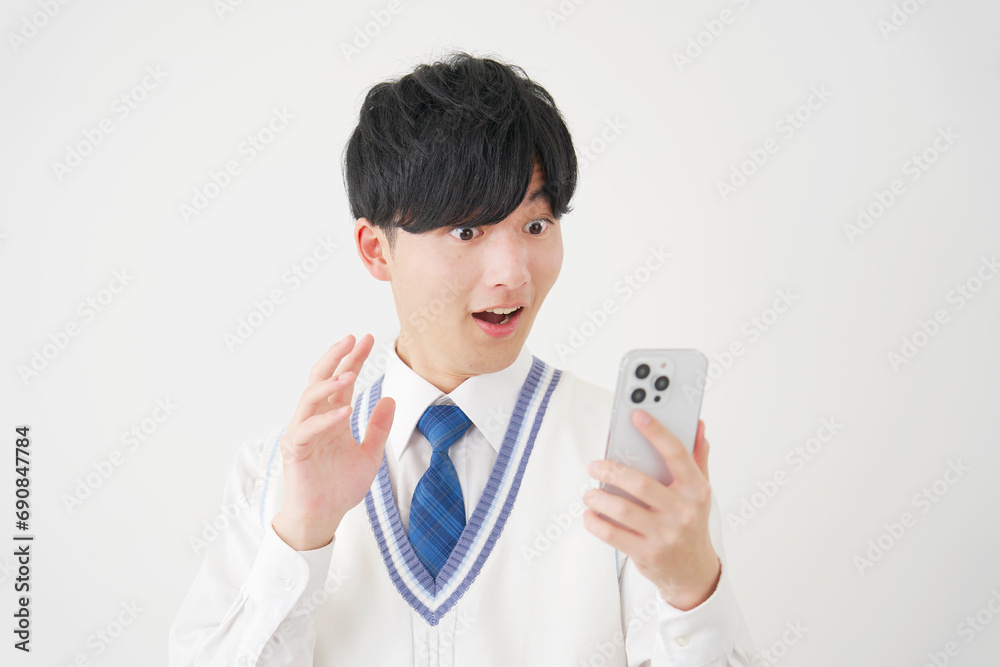 スマートフォンを見て驚く男子高校生 白背景 スマートフォンを見て驚く男子高校生 白背景