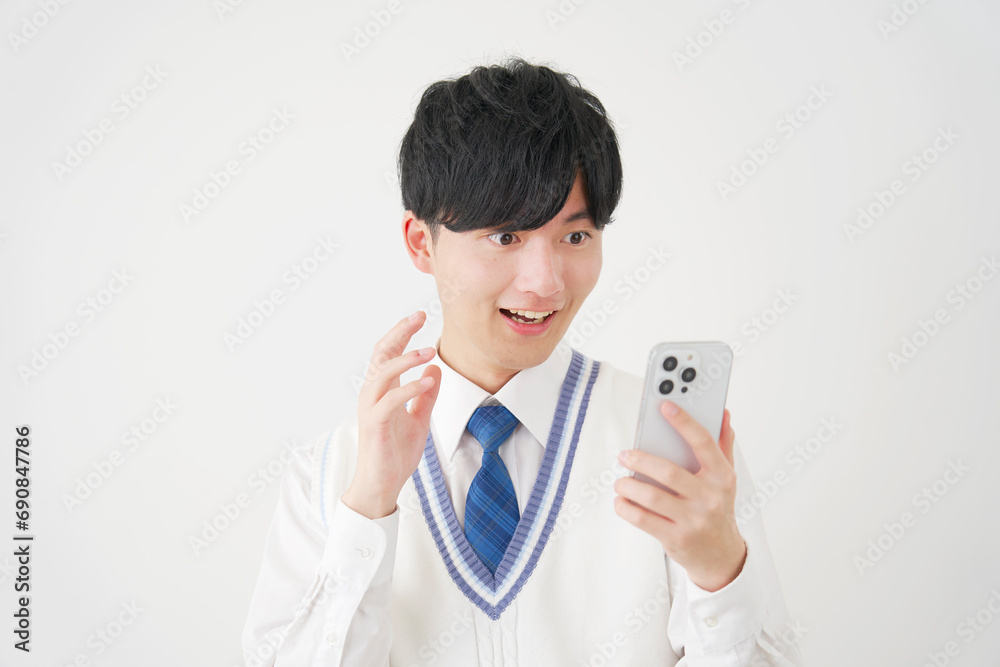 スマートフォンを見て驚く男子高校生 白背景 スマートフォンを見て驚く男子高校生 白背景