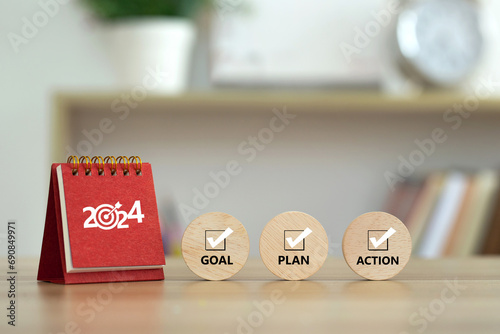 Happy New Year 2024 banner background. 2024 numbers year with target dart icon on red small desk calendar with Goal, Plan, Action on wooden cube. Business goals plan action and success concepts.