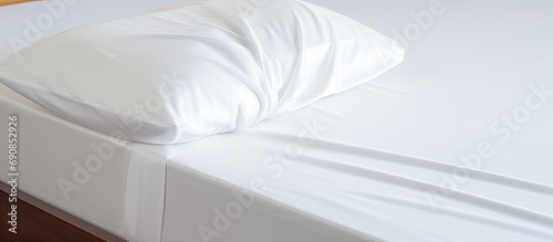 White fitted sheet on bed corner, with elastic band, covered by bed sheet. photo