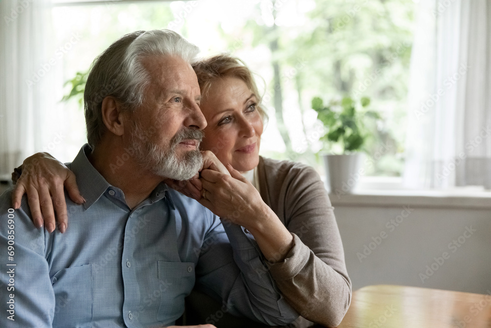 Dreams of mature love. Affectionate old age husband wife hug at cozy home look away dream recall good days of youth in memory. Caring senior spouses enjoy one another plan vacation together. Copyspace Dreams of mature love. Affectionate old age husband wife hug at cozy home look away dream recall good days of youth in memory. Caring senior spouses enjoy one another plan vacation together. Copyspace