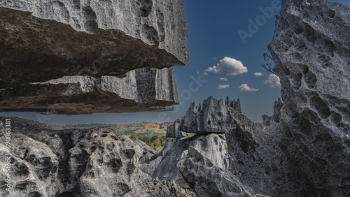 A unique natural formation is Tsingy De Bemaraha. Grey karst limestone cliffs with sharp peaks and bizarre outlines against a background of blue sky and clouds. Close-up. Madagascar. photo