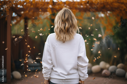 Fashion and style concept. Woman with white blank sweatshirt portrait. Girl standing back to camera in yellow autumn trees background. Model wearing white blank sweatshirt or sport jumper
