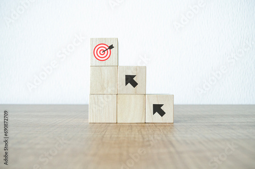 Hand putting virtual target board and arrow which print screen on wooden cube. Business achievement goal and objective target concept.