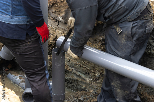 住宅の排水を下水道につなげる配管工事する人物 photo