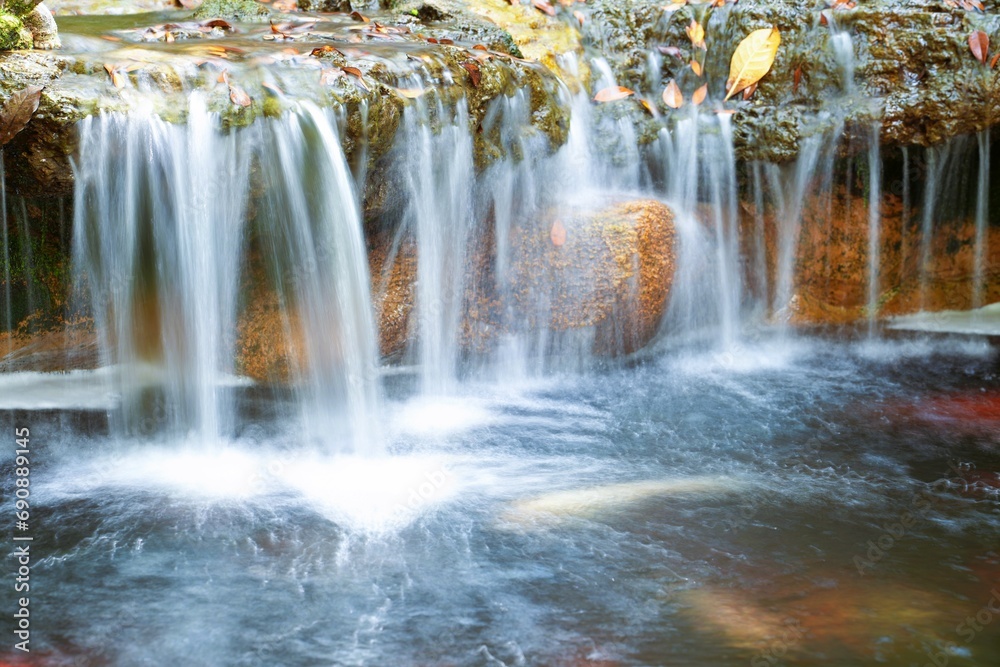 Obraz premium Large boulders are placed on the lower level of the waterfall.