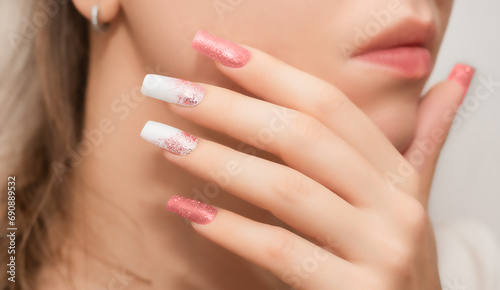 Female hands with long nails with glitter nail polish. Long nails peach color near face. Stylish fashion manicure. photo