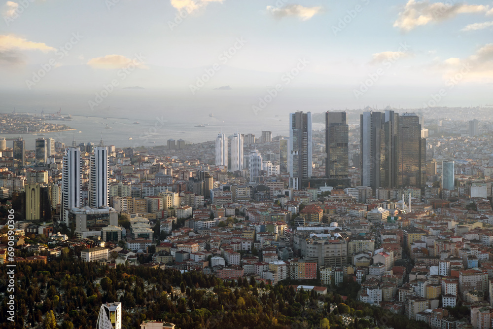 View from the window of a high-rise building to a modern city with skyscrapers, parks and sea coast.