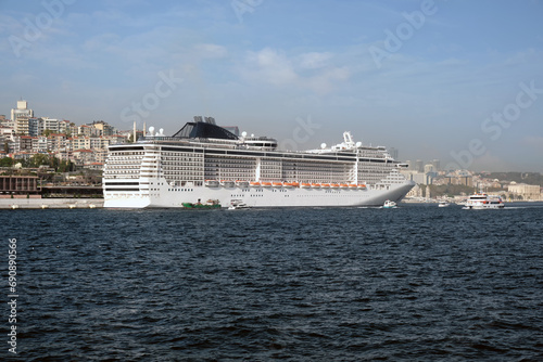 A large cruise ship stands on the pier with the city in the background. © SKfoto