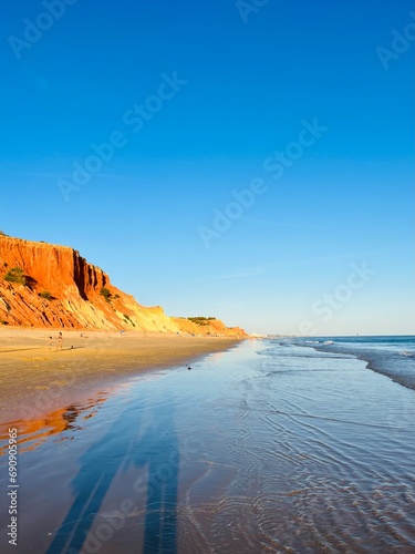 sandy ocean shoreline, ocean coast with orange rock © Oksana