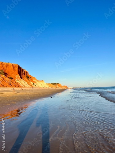 sandy ocean shoreline, ocean coast with orange rock