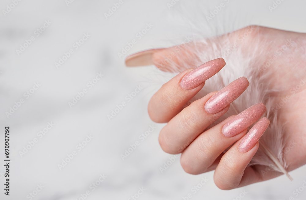 Female hands with pink nail design hold a feather Female hands with pink nail design hold a feather