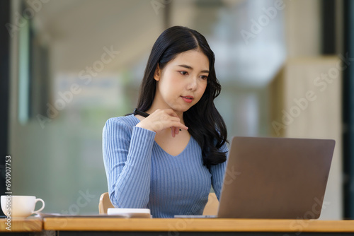 A beautiful woman uses her laptop while sitting in a chair at her workplace, Small business owner employees freelance online SME marketing e-commerce telemarketing concept.