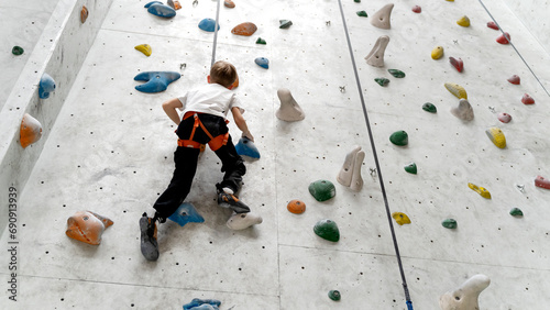 A boy or a girl climbing a climbing wall